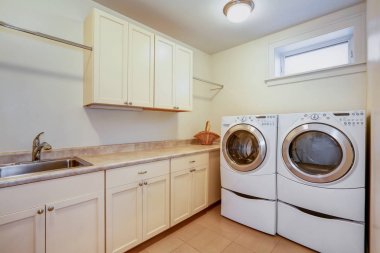Light laundry room with creamy cabinets. clipart