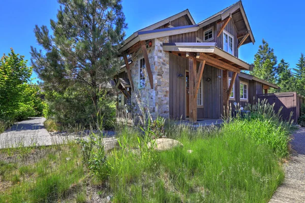夏天的时候 灰色的木制乡村房屋的正面装饰着松树 花卉和青草 — 图库照片