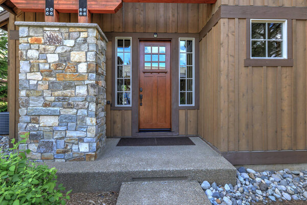 Front door with wooden elements and glass in natural style brown mountain home.