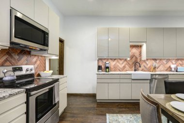 Eski köyün kırsal duvar resmiyle yemek odası ve modern mutfak parlak bej dolaplar, kırsal tuğla kaplama..