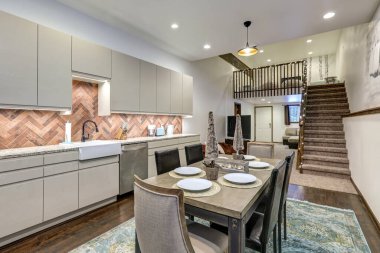 Eski köyün kırsal duvar resmiyle yemek odası ve modern mutfak parlak bej dolaplar, kırsal tuğla kaplama..