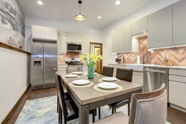 Eski köyün kırsal duvar resmiyle yemek odası ve modern mutfak parlak bej dolaplar, kırsal tuğla kaplama..