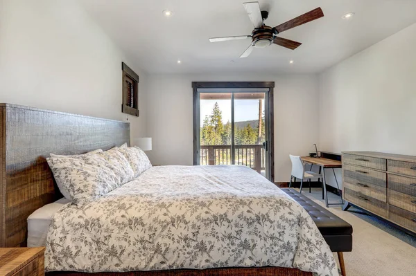 Natural tones cozy bedroom interior with grey bedding, beige carpet and lots of windows.