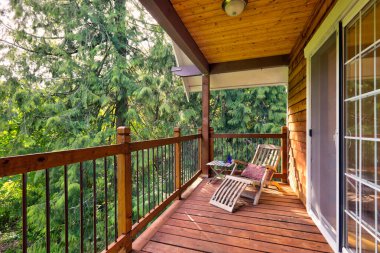 Sedir ahşap ahşap, yeşil doğası olan büyük bir Amerikan evi extrior ve oturma koltuğu ve güneş ışığı olan rahat bir balkon..