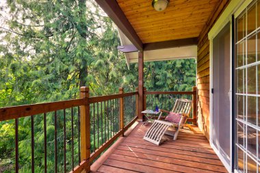 Cedar wooden large American house extrior with green nature and cozy private balcony with sitting chair and sunlight. clipart