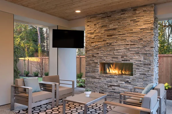 Outdoor Luxury living room cozy space covered with wood ceiling, stone fireplace, TV and natural beige rug.