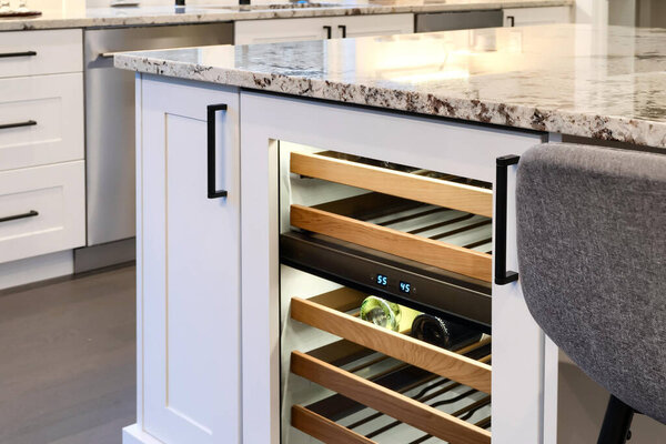 Corner details of white cabinets with drink fridge in the kitchen.