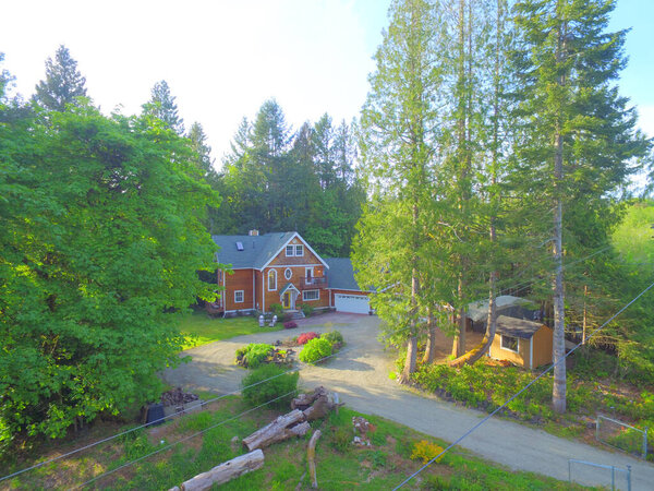 Wooden большой американский дом с естественным коричневым тоном с белой отделкой и зеленой летней природой с двойным гаражом
.