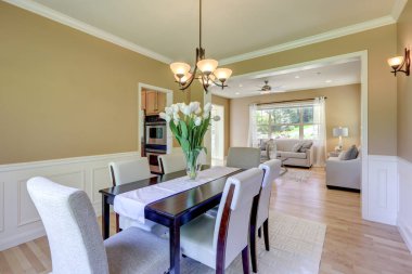 Klasik hardal rengi ve gri tonlu yemek odası. Büyük masa ve keten sandalyeler..