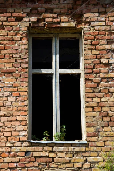 Old window without glass in the house of bricks
