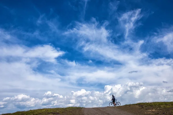 Rowerzysta na horyzoncie na tle chmur. — Zdjęcie stockowe