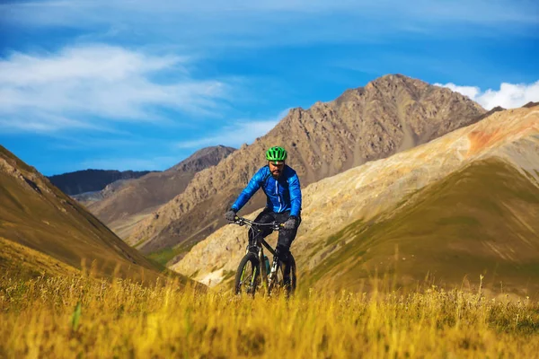 Bir adam dağlarda bir Bisiklete biniyor. Burkan Nehri Vadisi. Kırgızistan