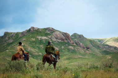 Binici at sırtında. Yaz intermontane bir vadide ovalar. Kazakistan
