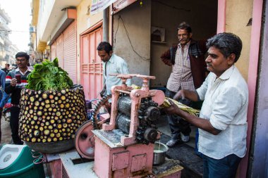 Jaipur, Hindistan - 10 Ocak 2018: Erkekler doğal taze şeker kamışı suyu ile mekanik bir aygıt sıkmak..
