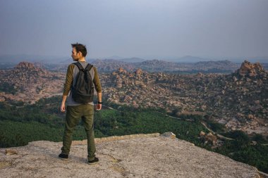 Bir tepenin kenarında duran turist. Matanga tepesinden Hampi 'nin harabelerinin güzel manzarası. Karnataka, Hindistan