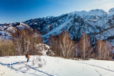 Genç bir adam kışın karlı dağlarda kayaklarla seyahat eder.