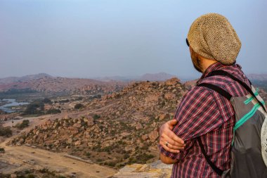 Bir tepenin kenarında duran turist. Matanga tepesinden Hampi 'nin harabelerinin güzel manzarası. Karnataka, Hindistan