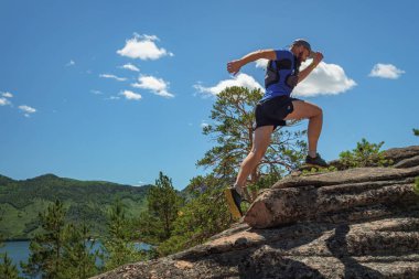 Koşucu Kaya 'ya Tırmanıyor. Sporcu dağlarda kayalarda koşar. Açık alan yolu çalışıyor