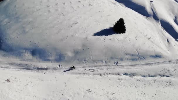 冬季骑摩托车的人骑在高山上 摩托车几乎不能在雪地里爬行 被群山和冷杉所环绕 鸟瞰全景 — 图库视频影像