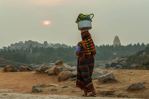 Hintli bir kadın kafasında ağır bir yük taşır. Hindistan. Karnataka
