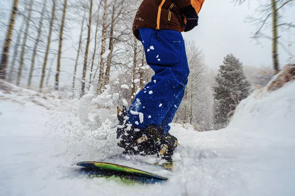 El primer plano de una tabla de snowboard se desliza con salpicaduras de nieve —  Fotos de Stock