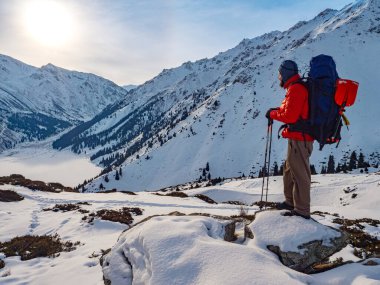 A tourist among the magnificent mountain landscape and the lake covered with ice