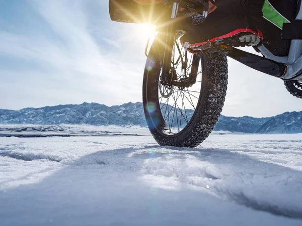 Close-up of a fatbike wheel, rolling on a frozen mountain lake.