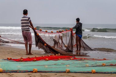 Fishermen on the seashore pull out nets