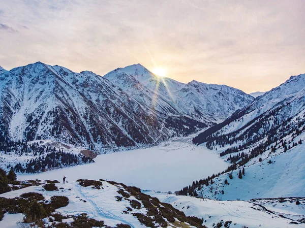 Ein Reisender trifft im Winter die Morgendämmerung auf einem Bergsee — Stockfoto
