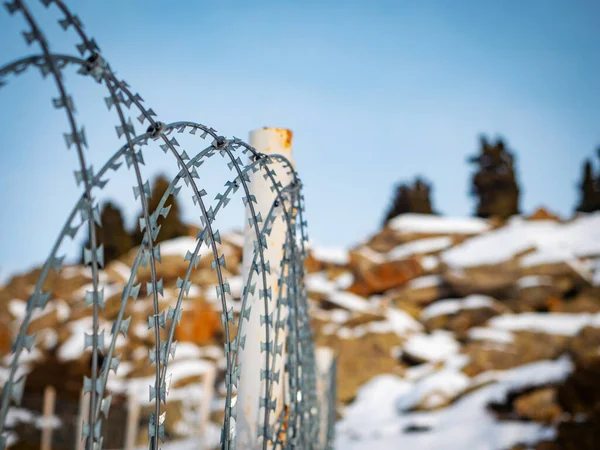 Barbed wire fence. Fence against the backdrop of snowy mountains