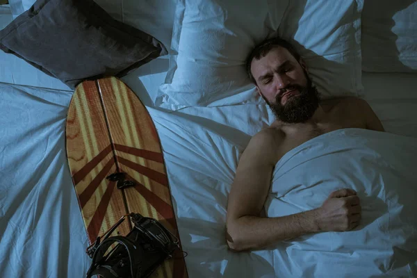 A man sleeps in the blood with his beloved snowboard