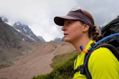 Dağlarda sırt çantalı genç bir turist kızın portresi. Yüksek dağlarda gezinti. Aktif kız yaşam tarzı