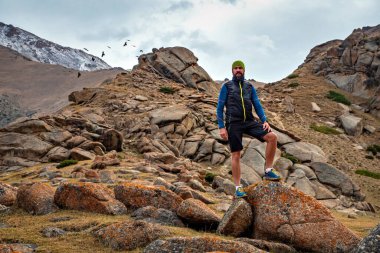 Sakallı bir erkek koşucunun portresi. Dağlarda yükseklerde koşuyor. İz çalışıyor