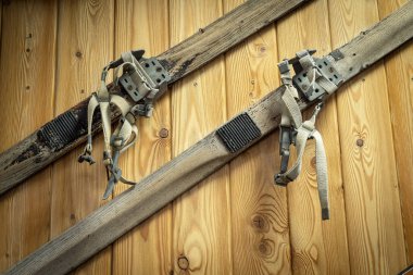 Tahta bir duvarda eski tip kayak asılı duruyor. Geçen yüzyılın spor malzemeleri.