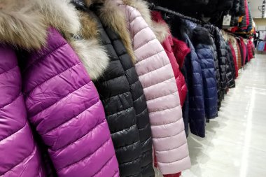Mağazadaki kadınlar için kürklü uzun renkli ceketler.