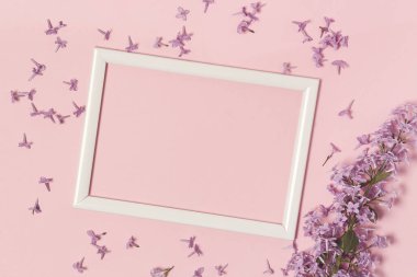 Boş fotoğraf çerçevesi ve pembe kağıt yüzeyinde leylak çiçekleri