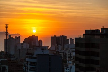 LIMA / PERU - May 10 2016: A rooftop view of the skyscrapers and sunset over the Pacific Ocean in Lima, Peru.