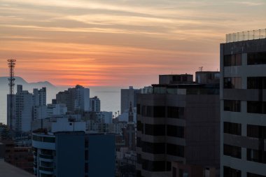 LIMA / PERU - May 10 2016: A rooftop view of the skyscrapers and sunset over the Pacific Ocean in Lima, Peru.
