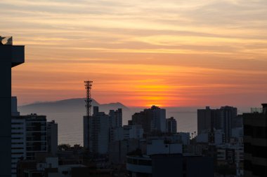 LIMA / PERU - May 10 2016: A rooftop view of the skyscrapers and sunset over the Pacific Ocean in Lima, Peru.