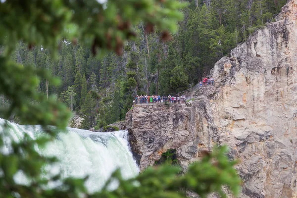 YELLOWSTONE NATIONAL PARK, USA - July 12 2014:  A group of tourists standing on a cliff at a viewpoint overlooking Lower Falls of the Yellowstone River in Yellowstone National Park, Wyoming on July 12, 2014.