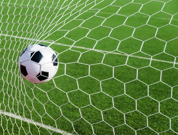 Soccer football in Goal net with green grass field. — Stock Photo, Image