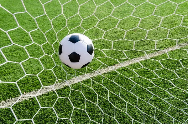 Soccer football in Goal net with green grass field. Royalty Free Stock Photos