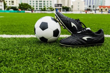 Futbol topu ve yeşil çim sahası üzerinde ayakkabı.