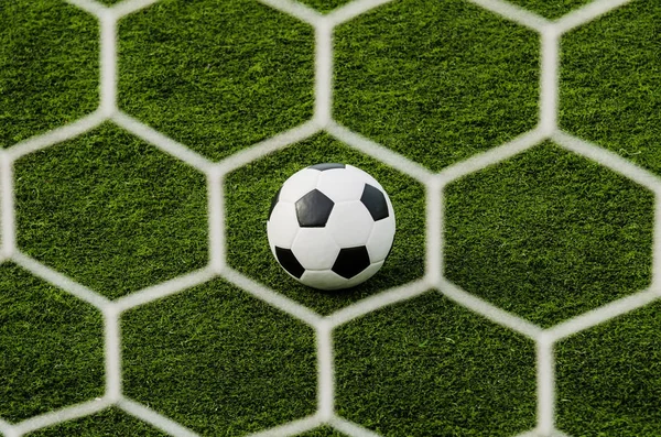 Fußball im Tornetz mit grünem Rasenfeld. — Stockfoto