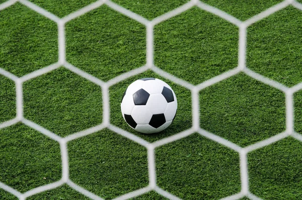 Fußball im Tornetz mit grünem Rasenfeld. — Stockfoto