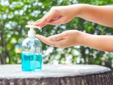 Kadının elleri ellerini temizlemek için bir şişe alkol jeline bastırıyor. Alkol jeli günlük hayatta çok önemlidir..