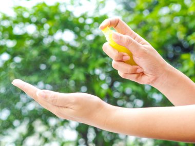 Kadınlar ellerini temizlemek için doğaya alkol spreyi sıkarlar. Alkol spreyi günlük hayatta çok önemlidir..