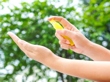 Kadınlar ellerini temizlemek için doğaya alkol spreyi sıkarlar. Alkol spreyi günlük hayatta çok önemlidir..