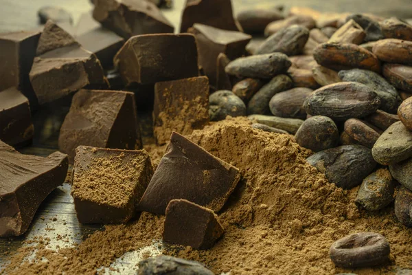 Stukjes chocolade met cacaobonen liggen op tafel — Stockfoto