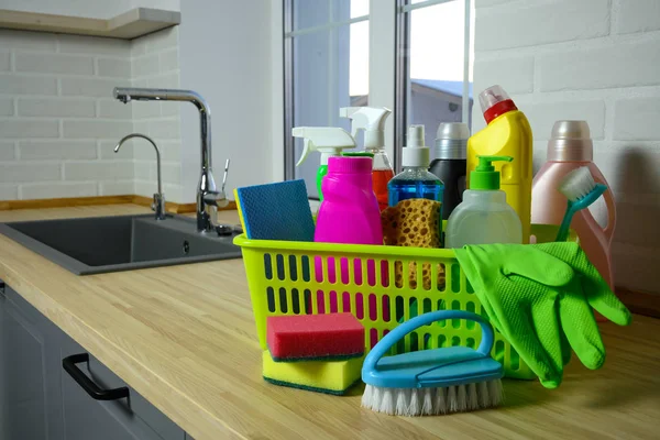 household chemicals in basket on kitchen background